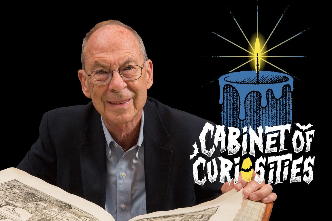 Henry Ansgar Kelly smiles while holding open a large illustrated book, posed against a black background alongside the "Cabinet of Curiosities" podcast logo depicting a lit blue candle. 
