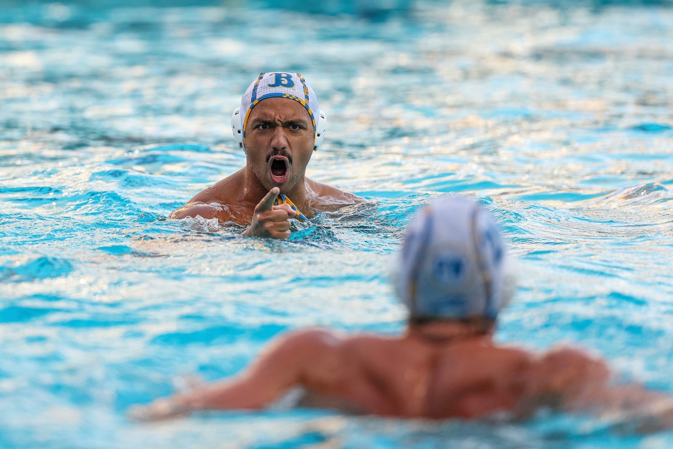 Jucá Carsalde of the men's water polo team points to a teammate in the pool