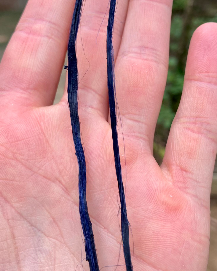 Close-up of blue threads held across a palm