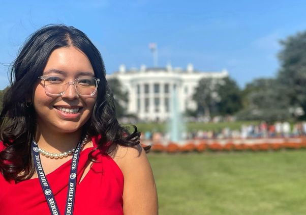 Head-and-shoulders shot of Cecy Rivera smiling with White House in background