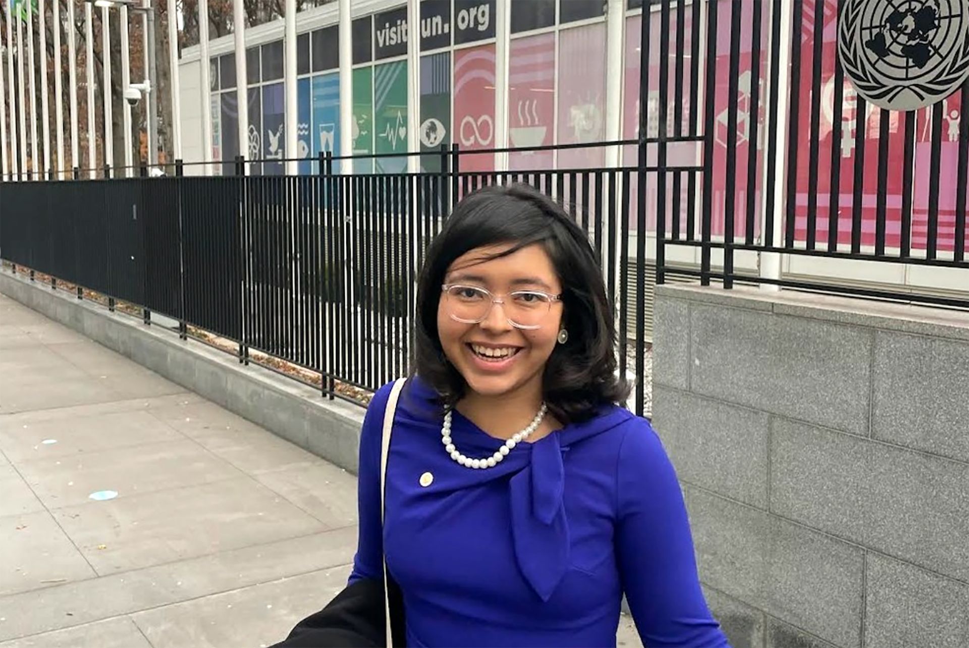 Cecy Rivera, in blue top and pearls, in front of the United Nations building