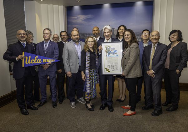 Julio Frenk, surrounded by UCLA leaders, holds up a proclamation welcoming him from the City Council