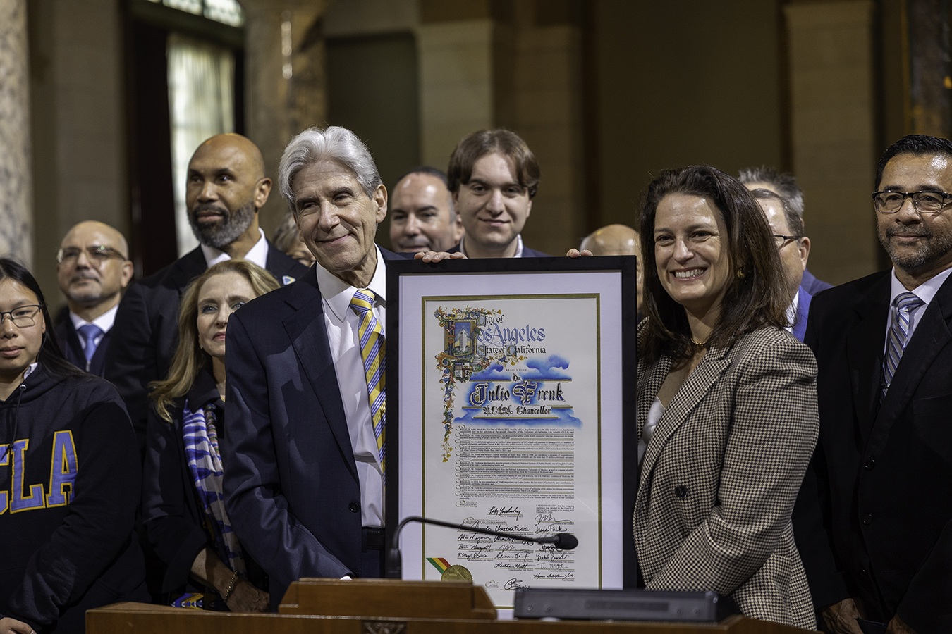 Julio Frenk and Los Angeles City Council member Katy Yaroslavsky, surrounded by supporters at City Hall, hold up the council’s proclamation welcoming Frenk to Los Angeles.