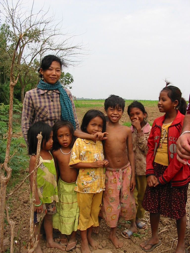 A mother stands with six children in a rice field