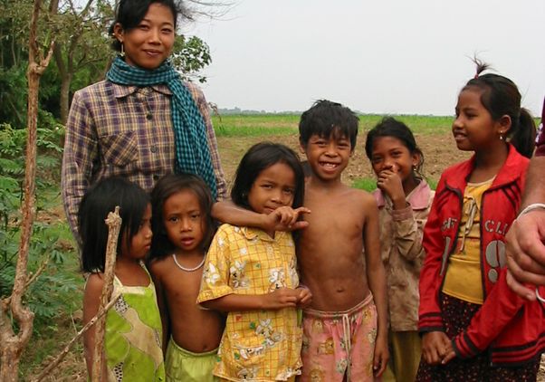 A mother stands with six children in a rice field