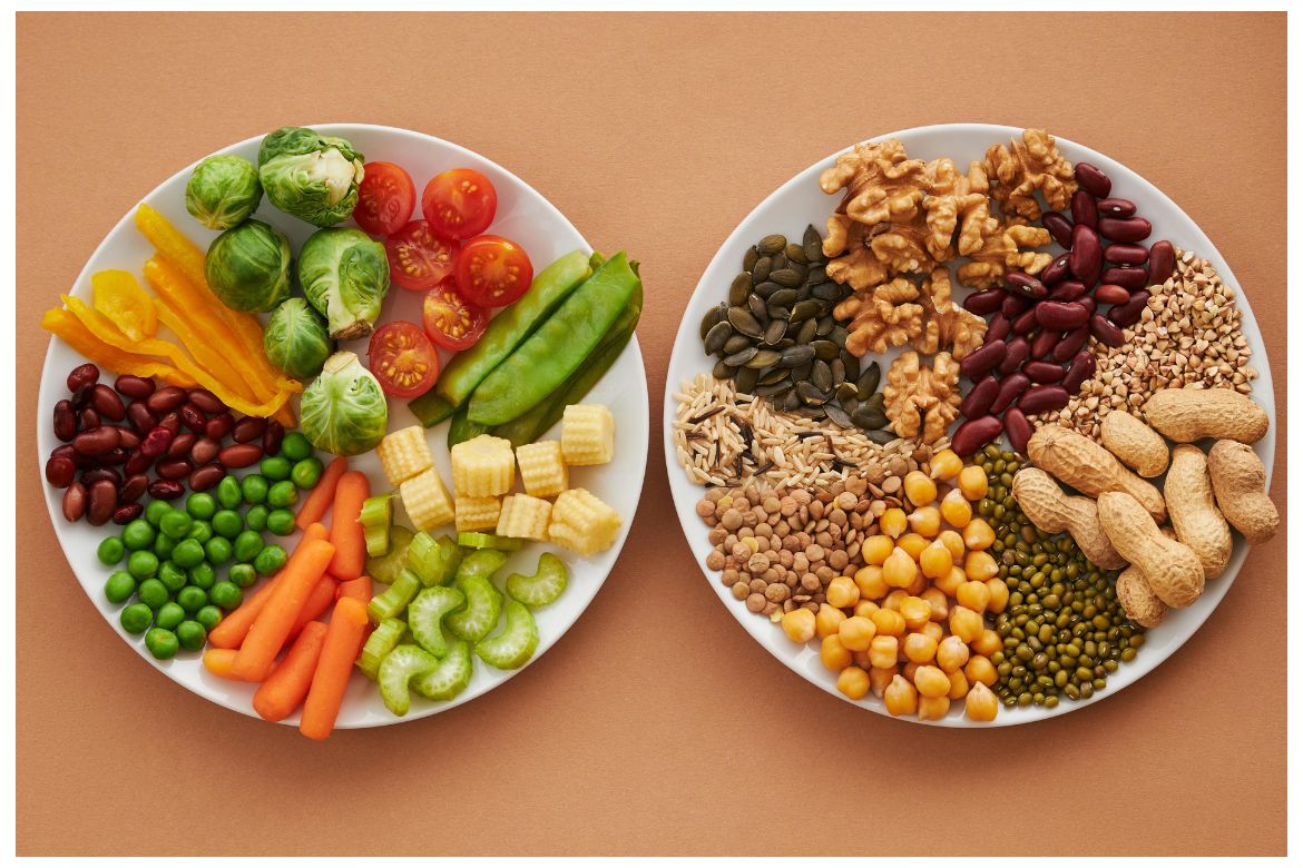 Two plates display vegetables and halved tomatoes, nuts and legumes including chickpeas and walnuts 
