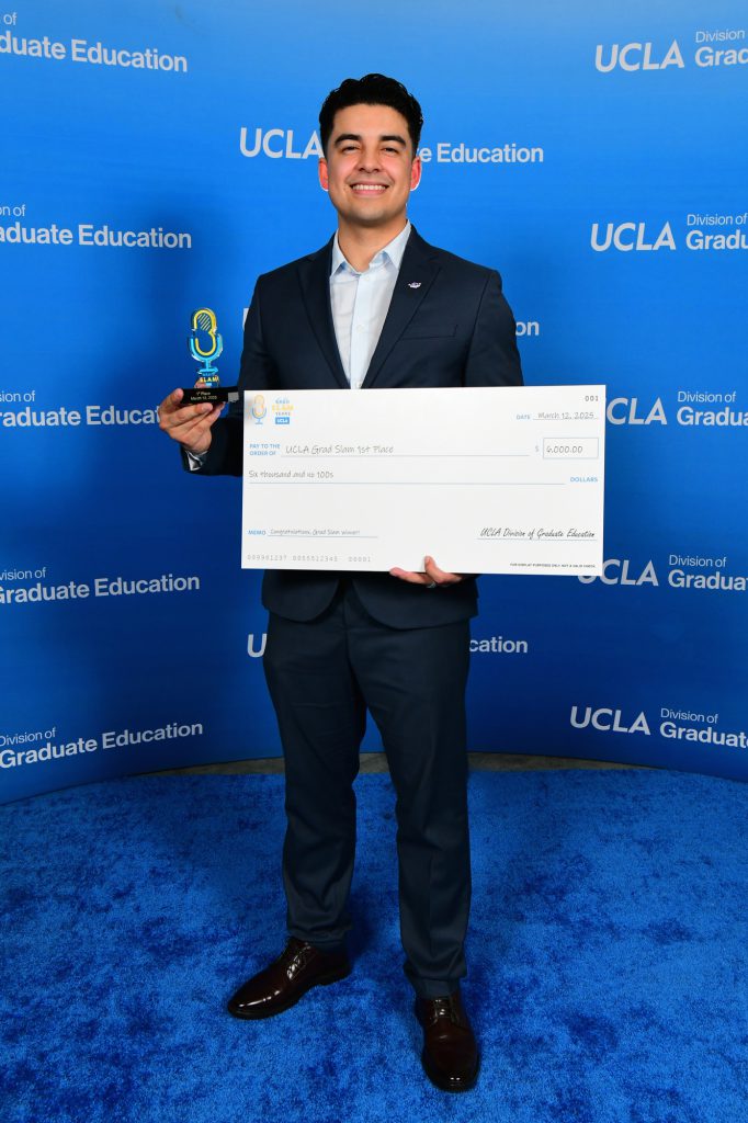 Pablo Alvarez holds his trophy from the UCLA Grad Slam competition and a ceremonial check