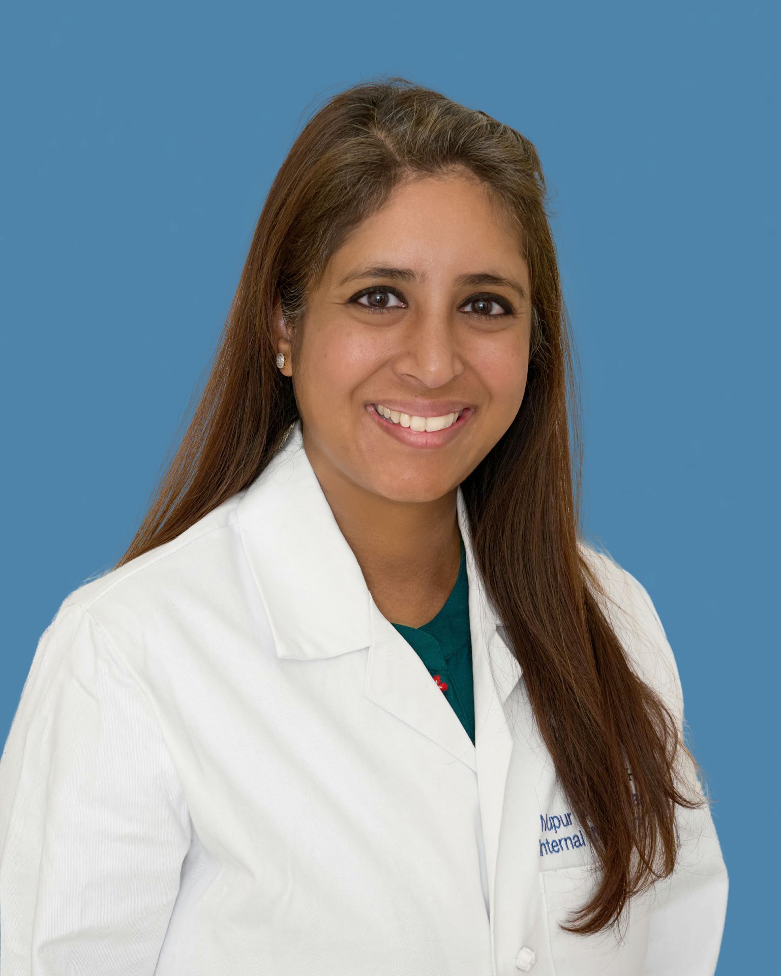 Nupur Agrawal, in white coat, against blue background 