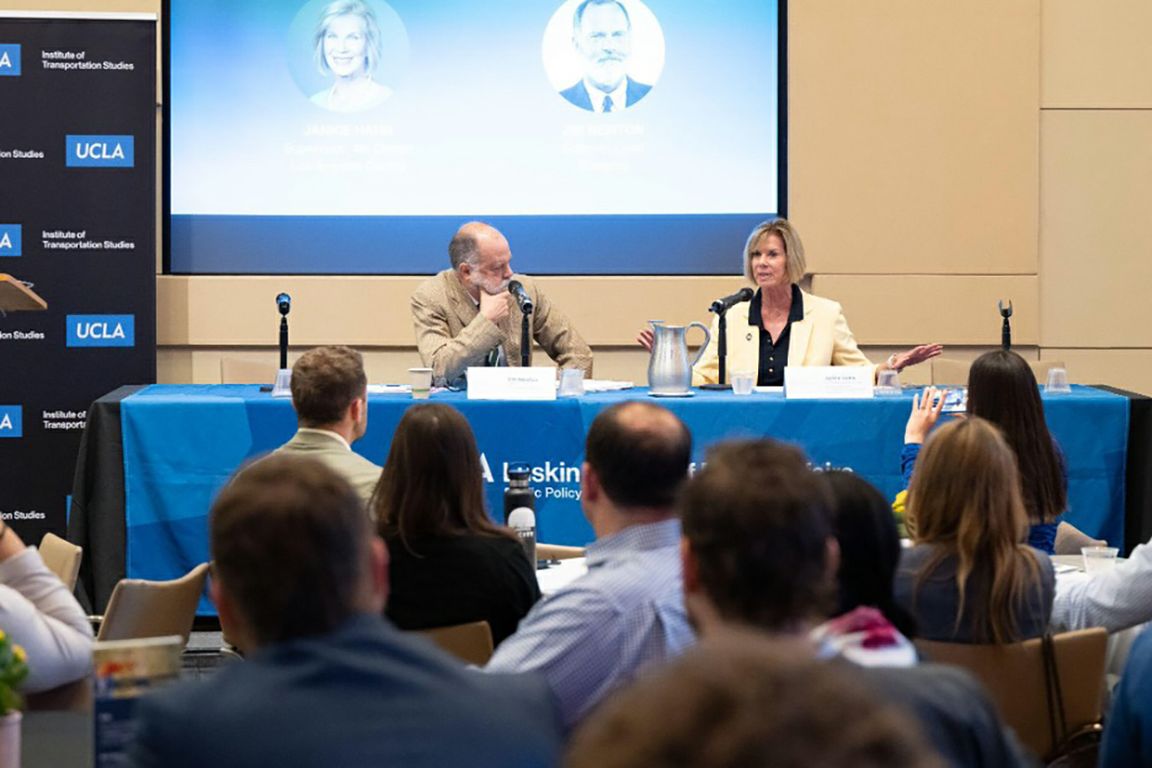 Jim Newton, left, and Janice Hahn sit in front of microphones at a long table