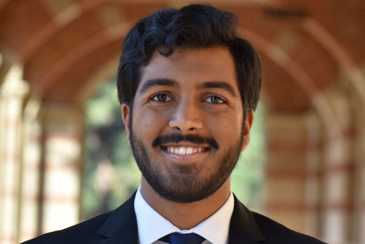 Headshot of Sohan Talluri smiling under a brick archway, wearing a dark suit and tie.