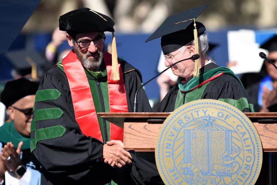 Richard Shemin, left, shakes hands with Steven Dubinett; both wear academic robes