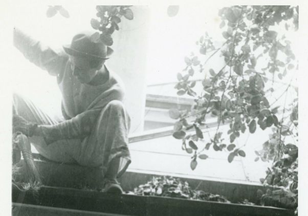 A black and white photo shows an adult Dorothy Arzner working on a home improvement project on her home's roof wearing a hat