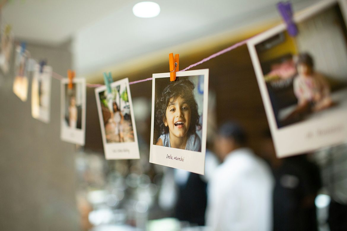 Polaroid photos on a string. Most of the images are blurry, but the clear one is the head of a smiling child.