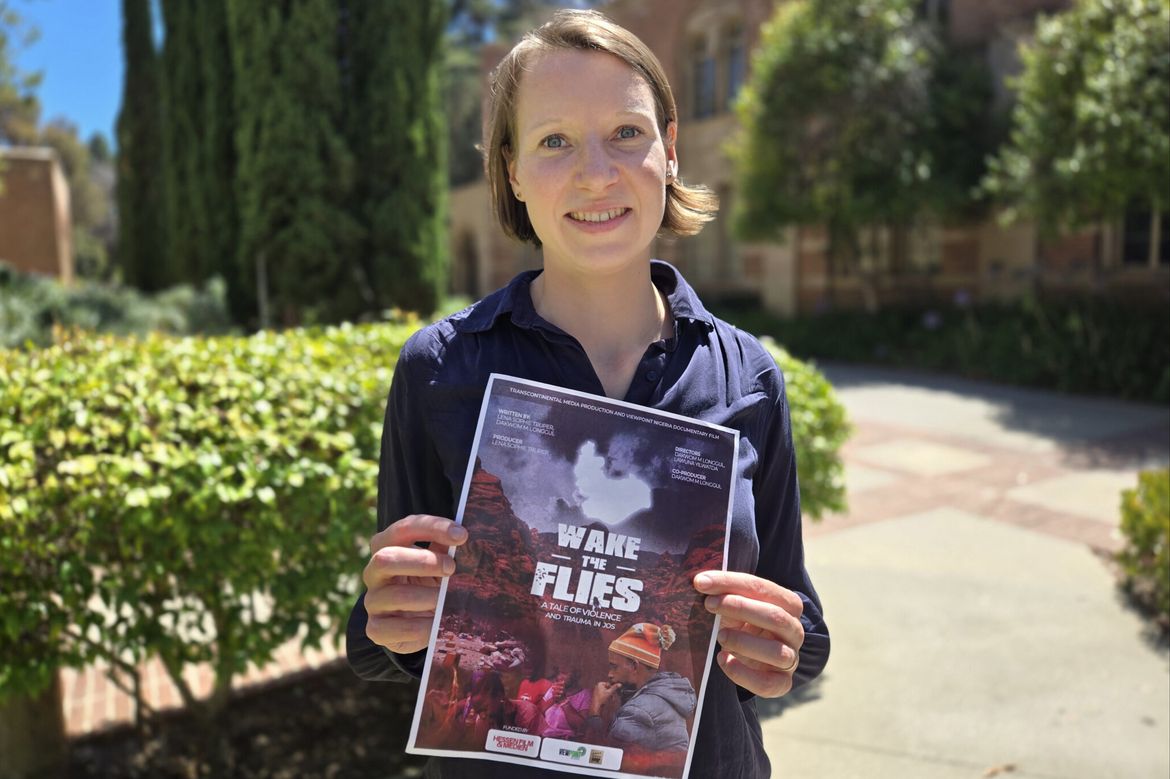 Lena Trüper, in dark blue top, holding up a flyer of "Wake the Flies"