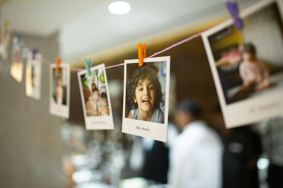 Polaroid photos on a string. Most of the images are blurry, but the clear one is the head of a smiling child.