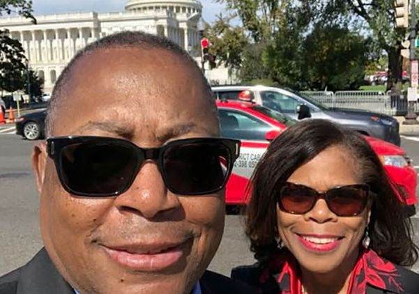 Close-up of Mel (left) and Cecelia Mann, wearing sunglasses and smiling in front of the U.S. Capitol Building in the background