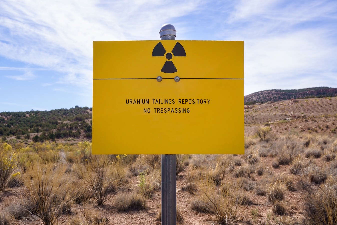 Sign in desert reading, "Uranium Tailings Repository / No Trespassing"