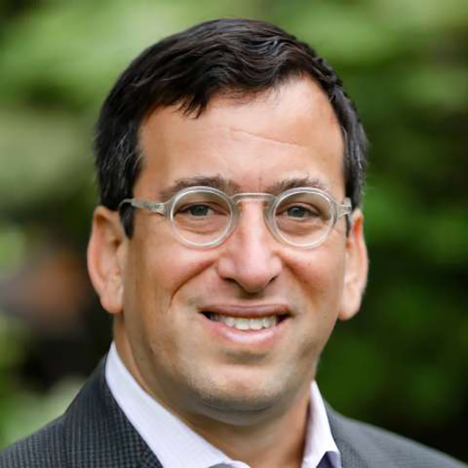 Close-up shot of Edward Garon in glasses and dark jacket