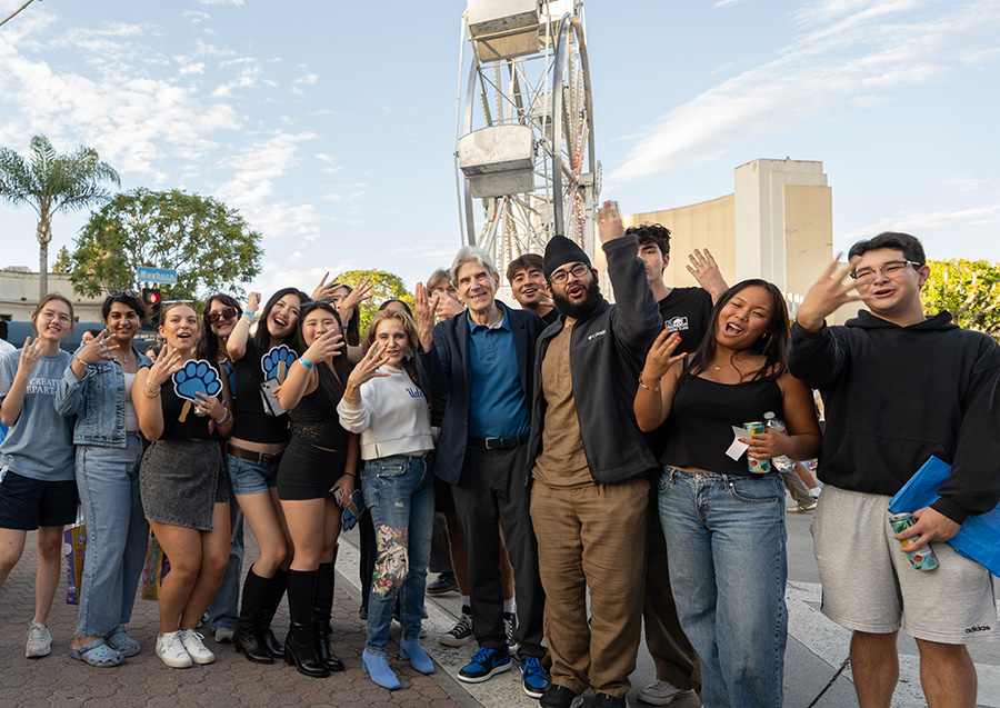 Chancellor Julio Frenk, Felicia Knaul and a group of students give the "fours up" hand signal at the block party in Westwood.    