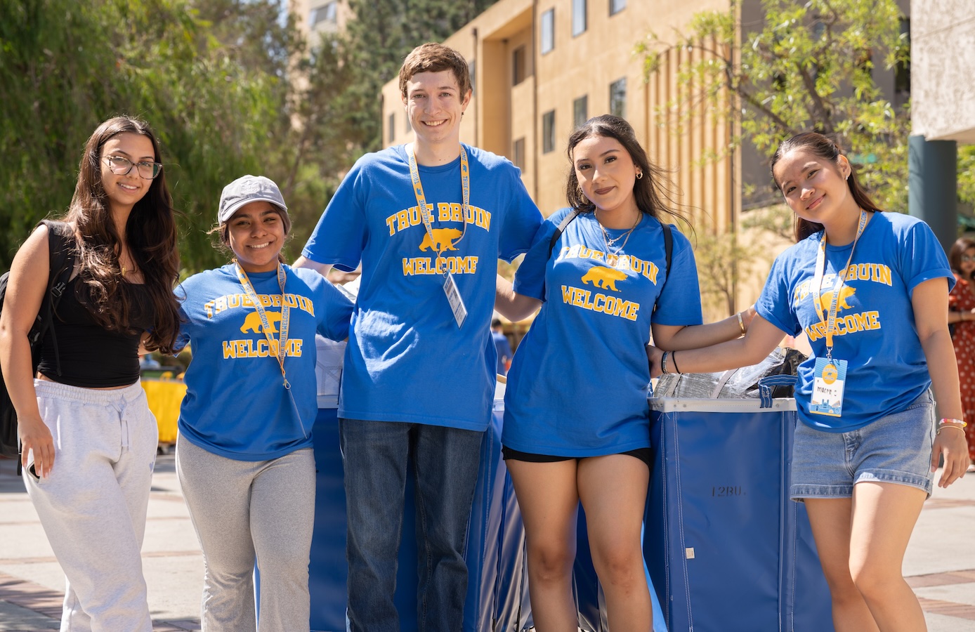 Move-in: Five students and volunteers stand in front of blue pushcarts