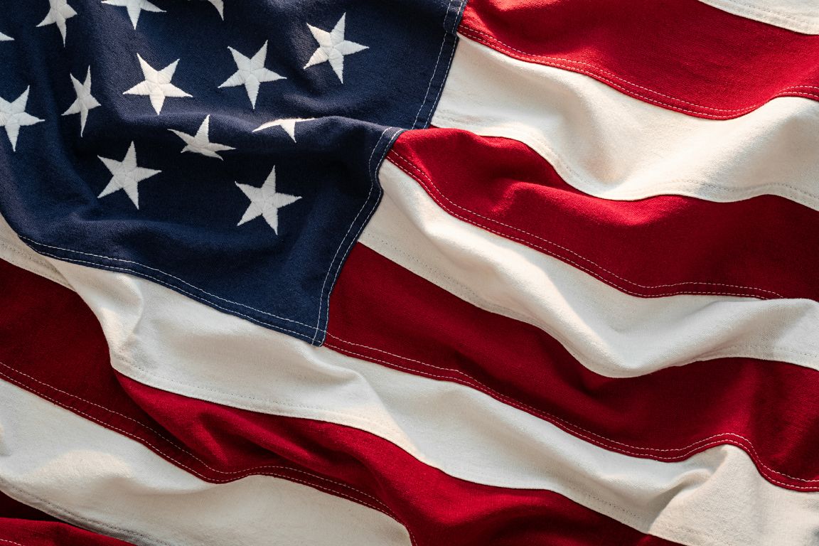  close-up of an American flag with red, white, and blue fabric visible, showing white stars on a blue field and alternating red and white stripes.