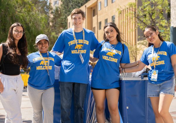 Move-in: Five students and volunteers stand in front of blue pushcarts