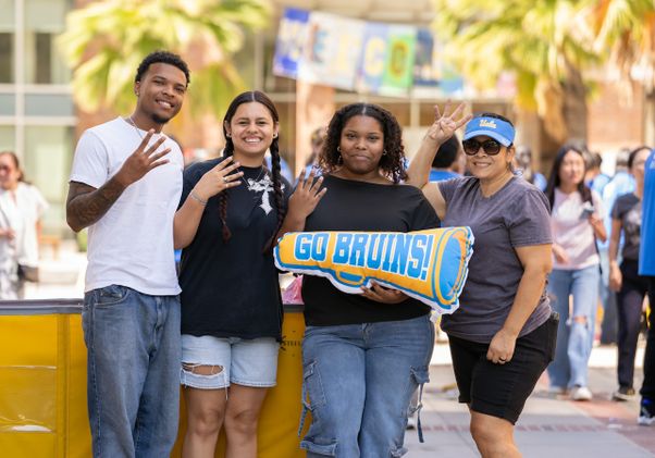 Move-in: Students give the fours-up while posing with "Go Bruins!" pillow