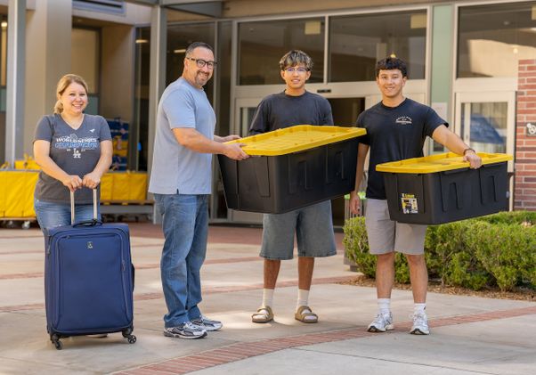 Move-in: Students and parents with suitcase and black moving bins