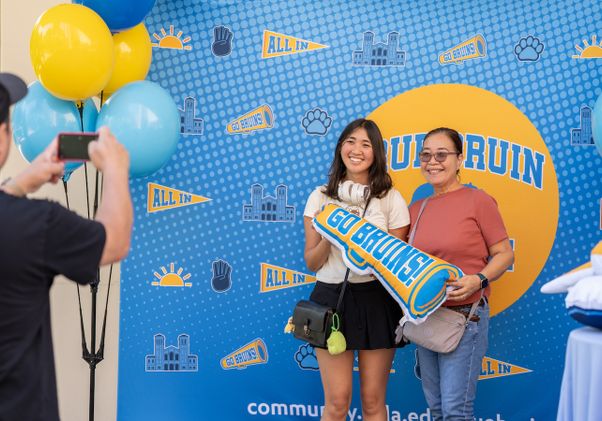 Move-in: Student and mother have photo taken in front of Bruin backdrop