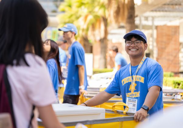 Move-in: Student volunteer smiles while gripping yellow pushcart