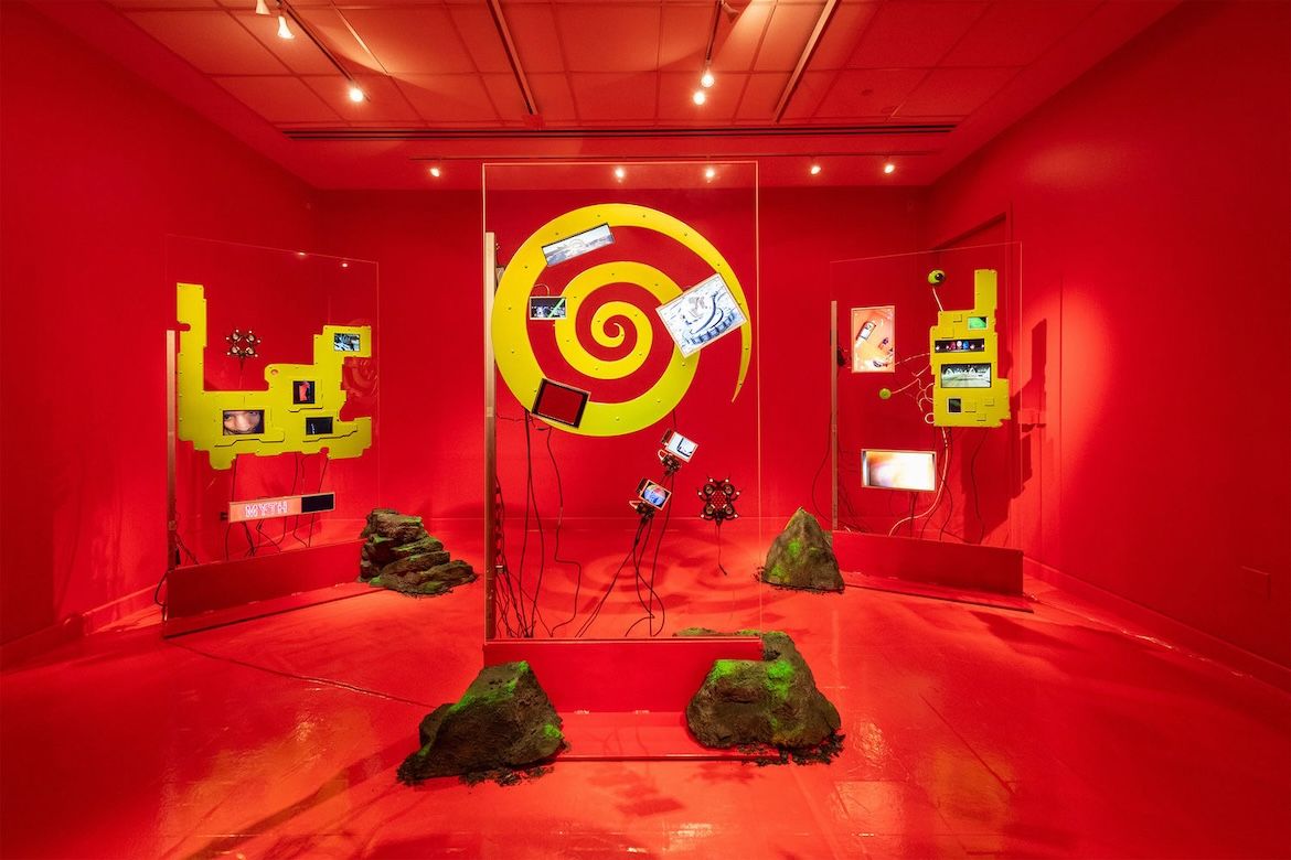 Three clear rectangular structures with yellow patterns painted on them in a red room