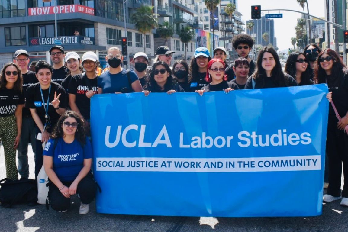 Department of Labor Studies gather around a blue banner 