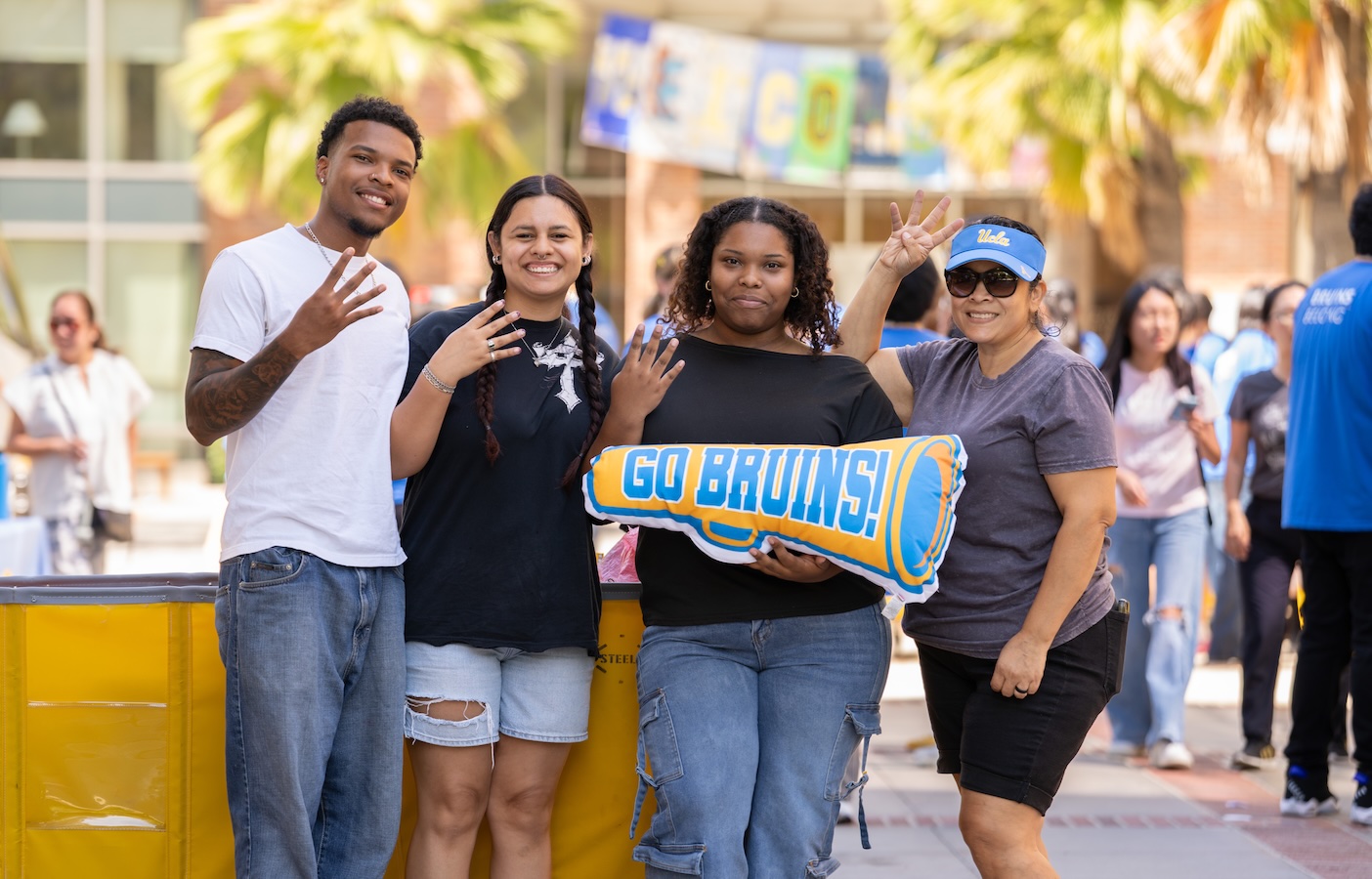 Move-in: Students give the fours-up while posing with "Go Bruins!" pillow