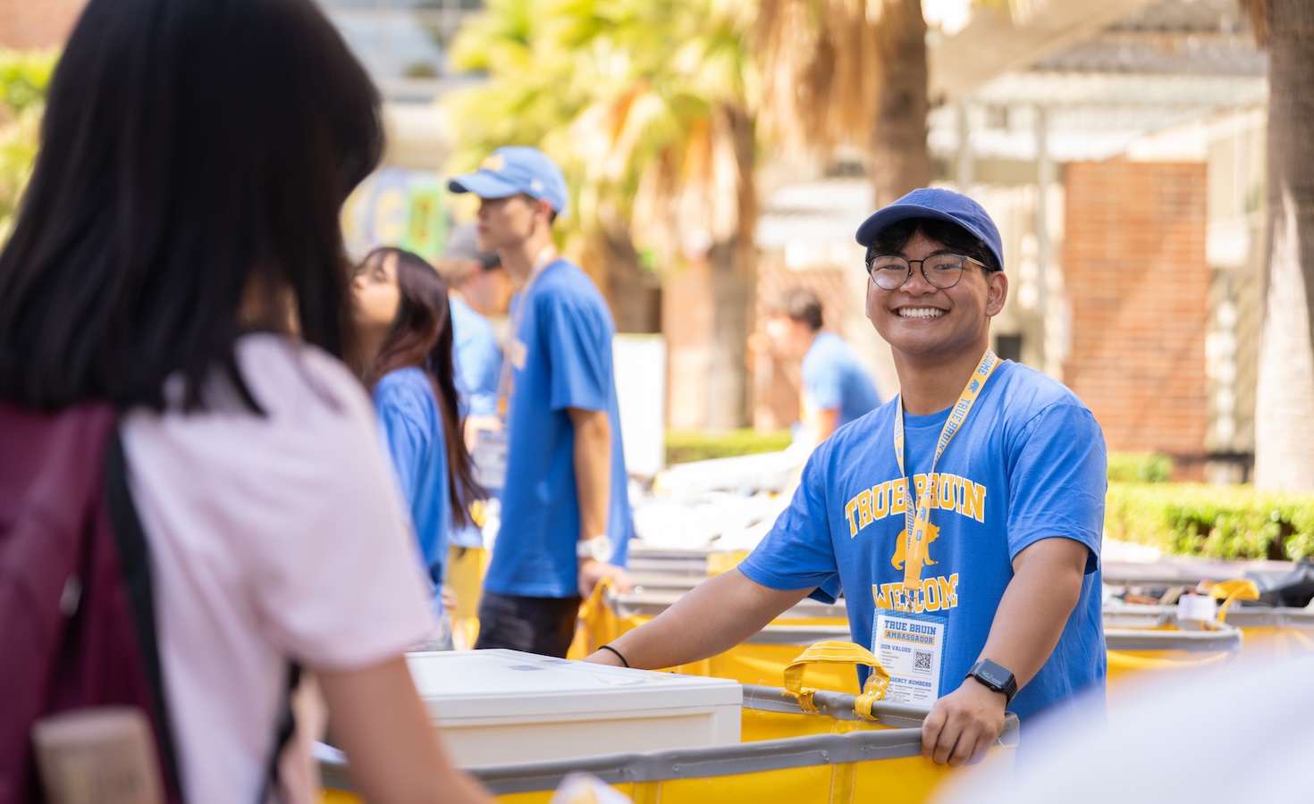 Move-in: Student volunteer smiles while gripping yellow pushcart