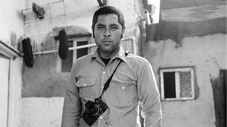 Black-and-white photo of Jason De León standing with camera around neck