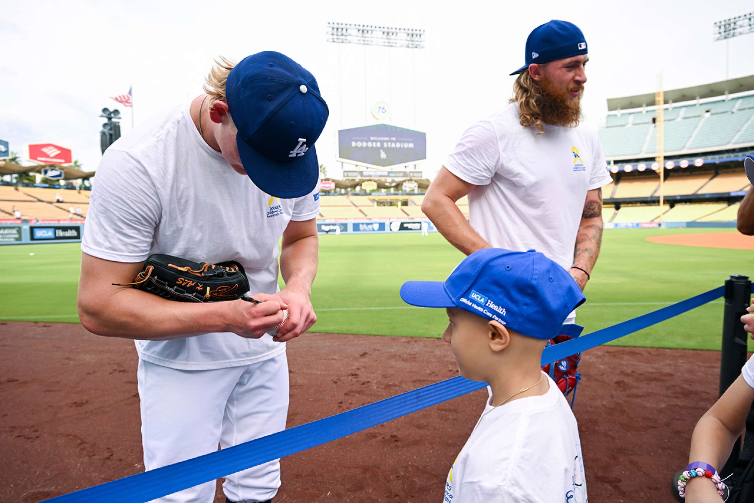 Emmet Sheehan signs an autograph for Mila Fuller, as Dodgers teammate Michael Kopech talks to guests. 