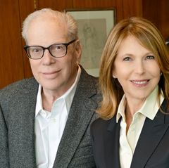 Midrange photo of Steven Gordon, left, in gray jacket, white shirt and glasses next to Laurie Gordon, in black jacket and off-white shirt