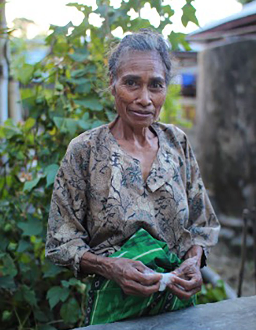 Midrange photo of a smiling woman outside wearing a brown-and-black patterned top