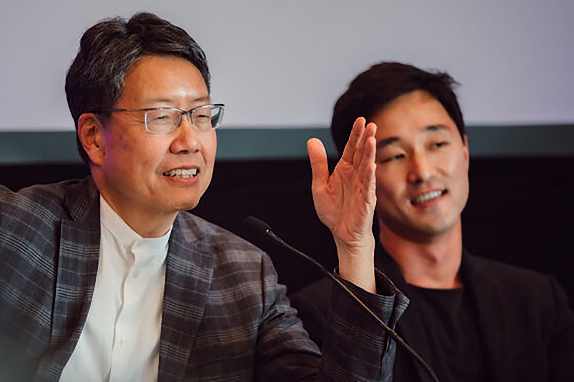 Kent Wong, left, in plaid jacket and white shirt, gestures with his left hand as he sits next to Ju Hong, in black