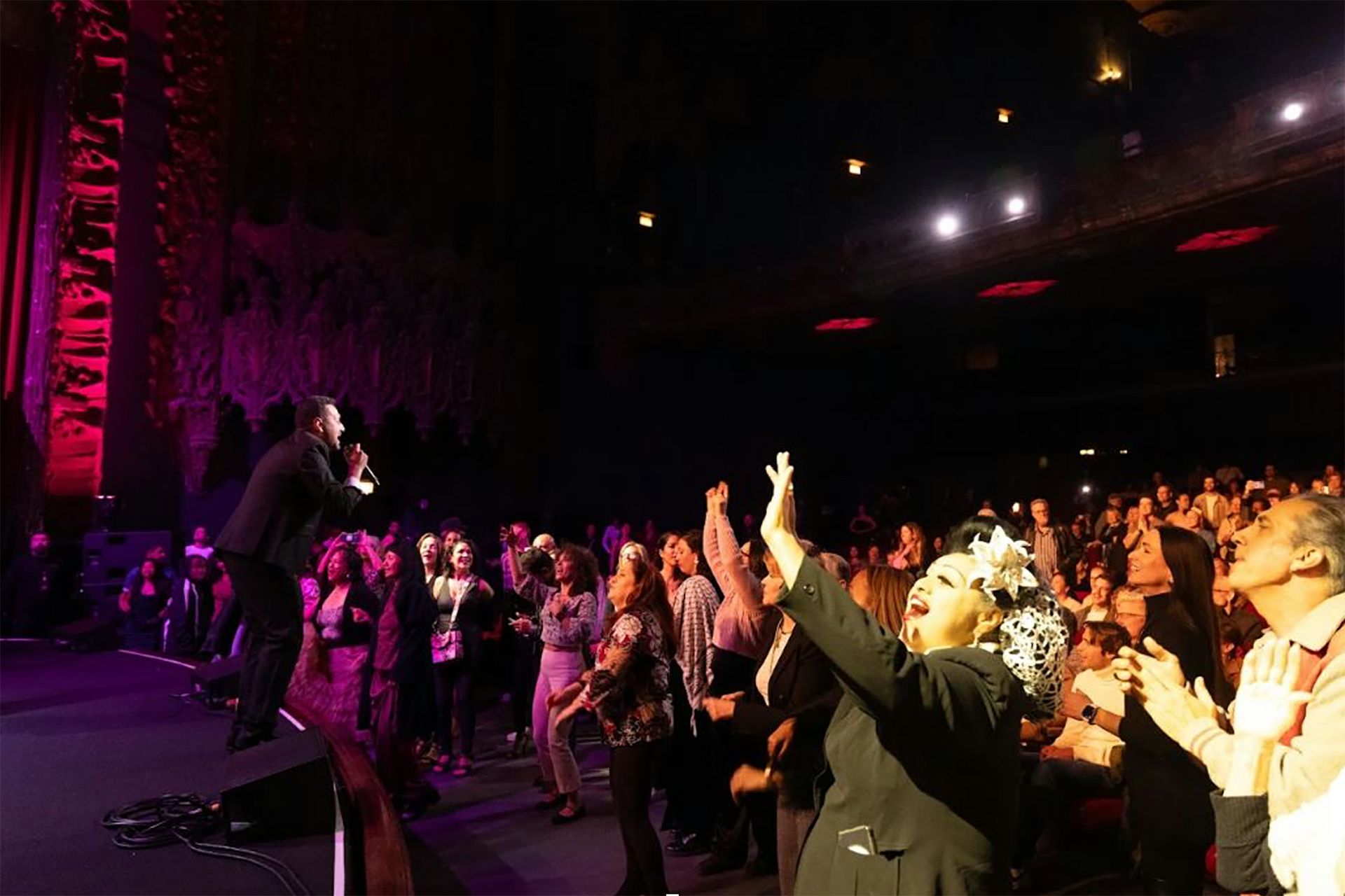 Orquesta Akokán, in dark suit, performs onstage in front of a standing crowd 