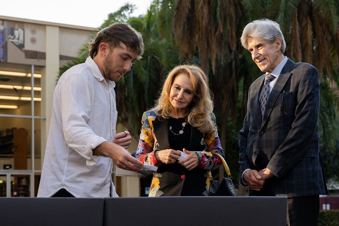 Chancellor Julio Frenk and Felicia Marie Knaul look on as a ceremony attendee sprinkles wildflower seeds into an outdoor planter at the UCLA Connects event.