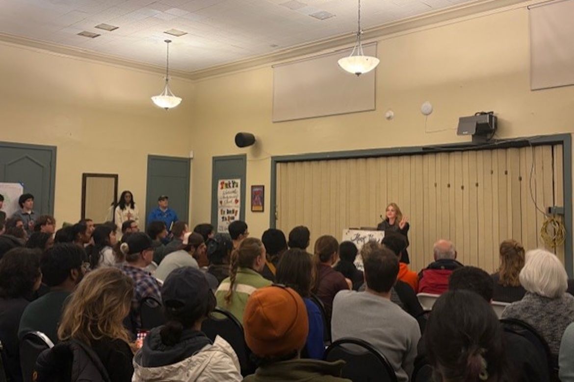 Felicia Knaul addresses a standing-room-only crowd from a podium at the front of a community hall during the Westwood Homeless Count volunteer gathering.
