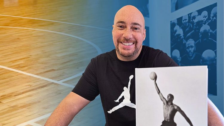 Adam Bradley, UCLA professor of English and African American studies, holding a photograph of a basketball player in a gym setting.