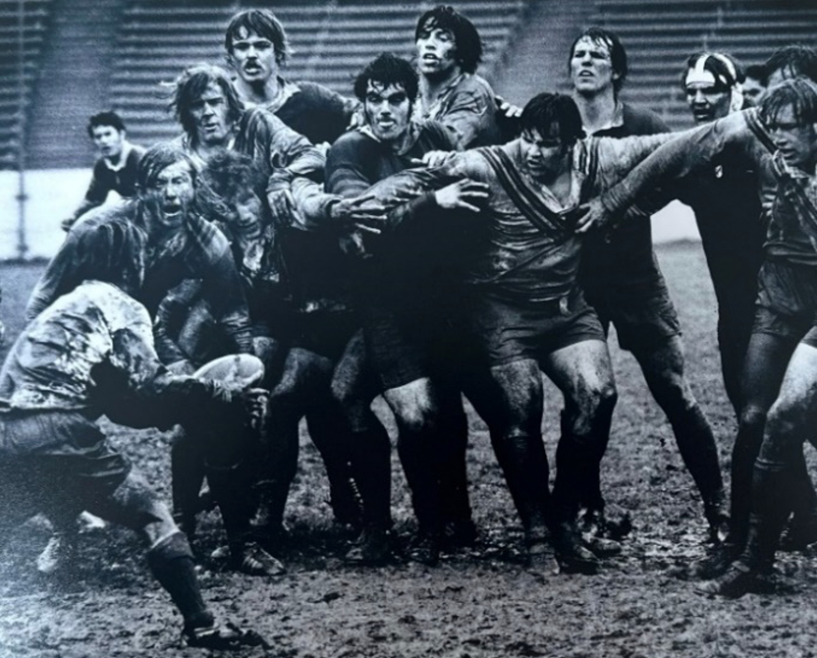 Black-and-white photo of rugby players in action on a muddy field
