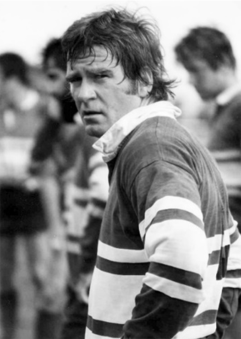 Black-and-white midrange photo of Larry Layne in rugby shirt looking over his left shoulder