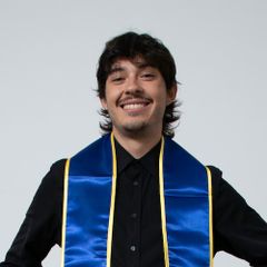 Headshot of Gabriel Portilla, smiling, wearing a black shirt and blue and gold graduation stole against a light background.