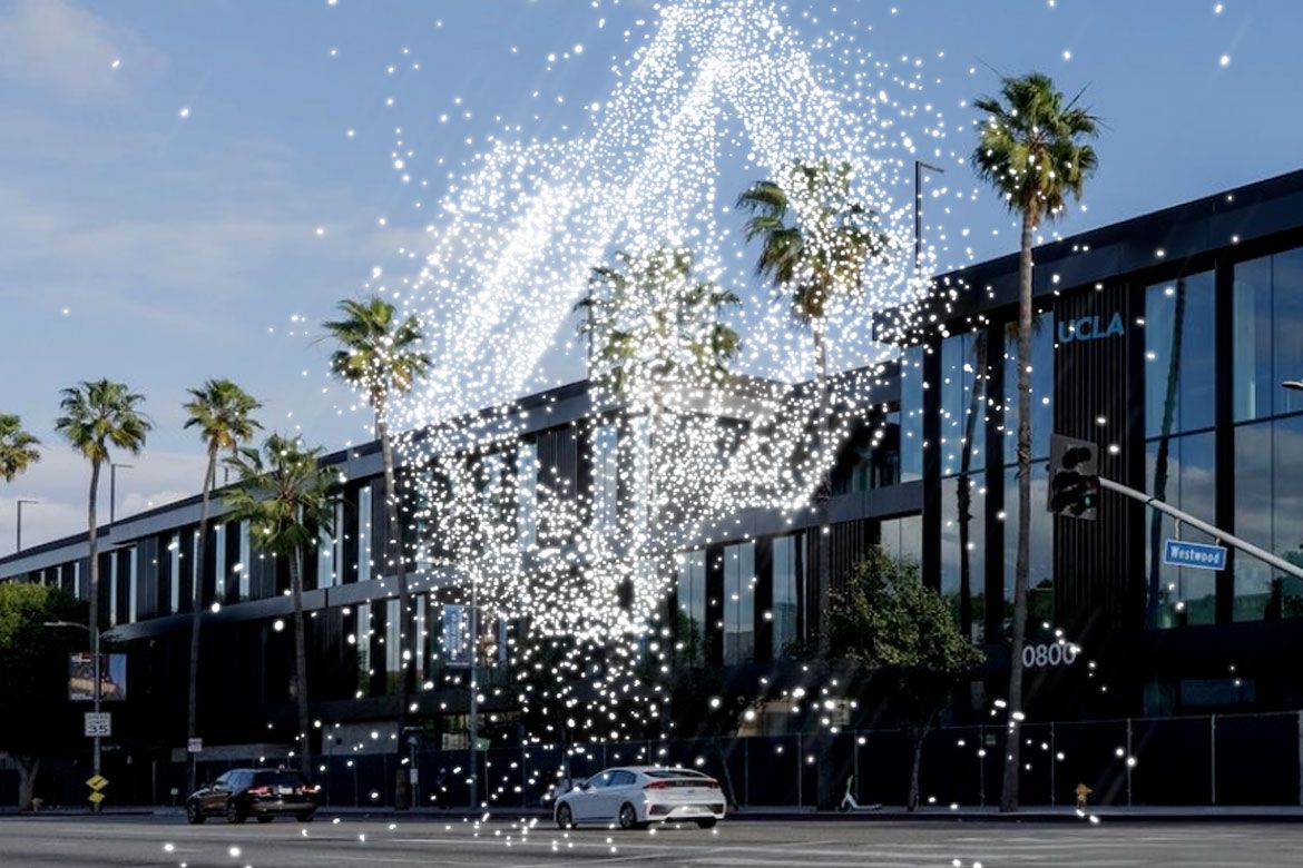 A photo illustration of the UCLA Research Park building on Westwood Boulevard, with a swirling stream of glowing white particles overlaid to represent quantum technology, with palm trees lining the street.