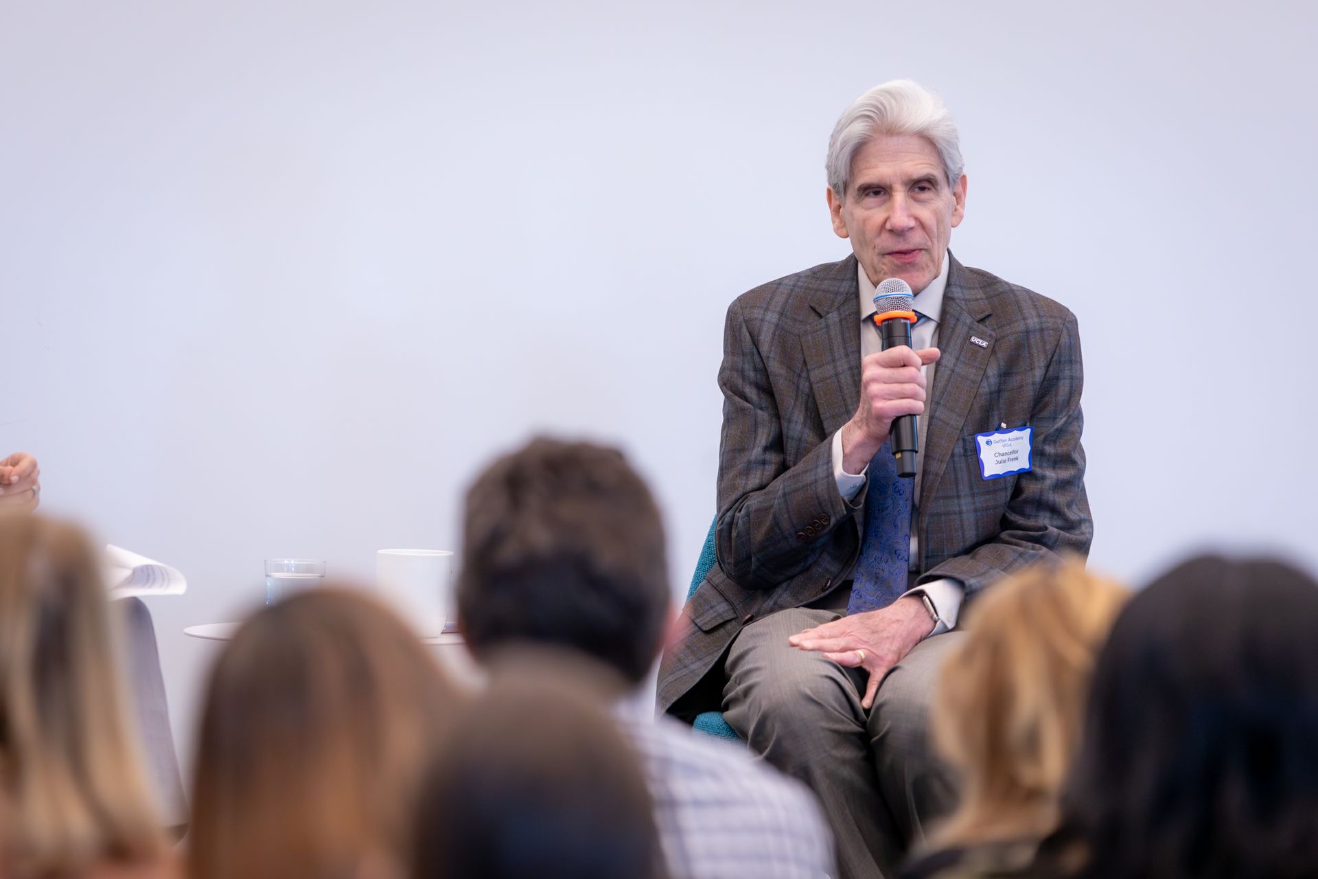 Chancellor Julio Frenk speaking into a microphone while seated before an audience at the Geffen Academy.