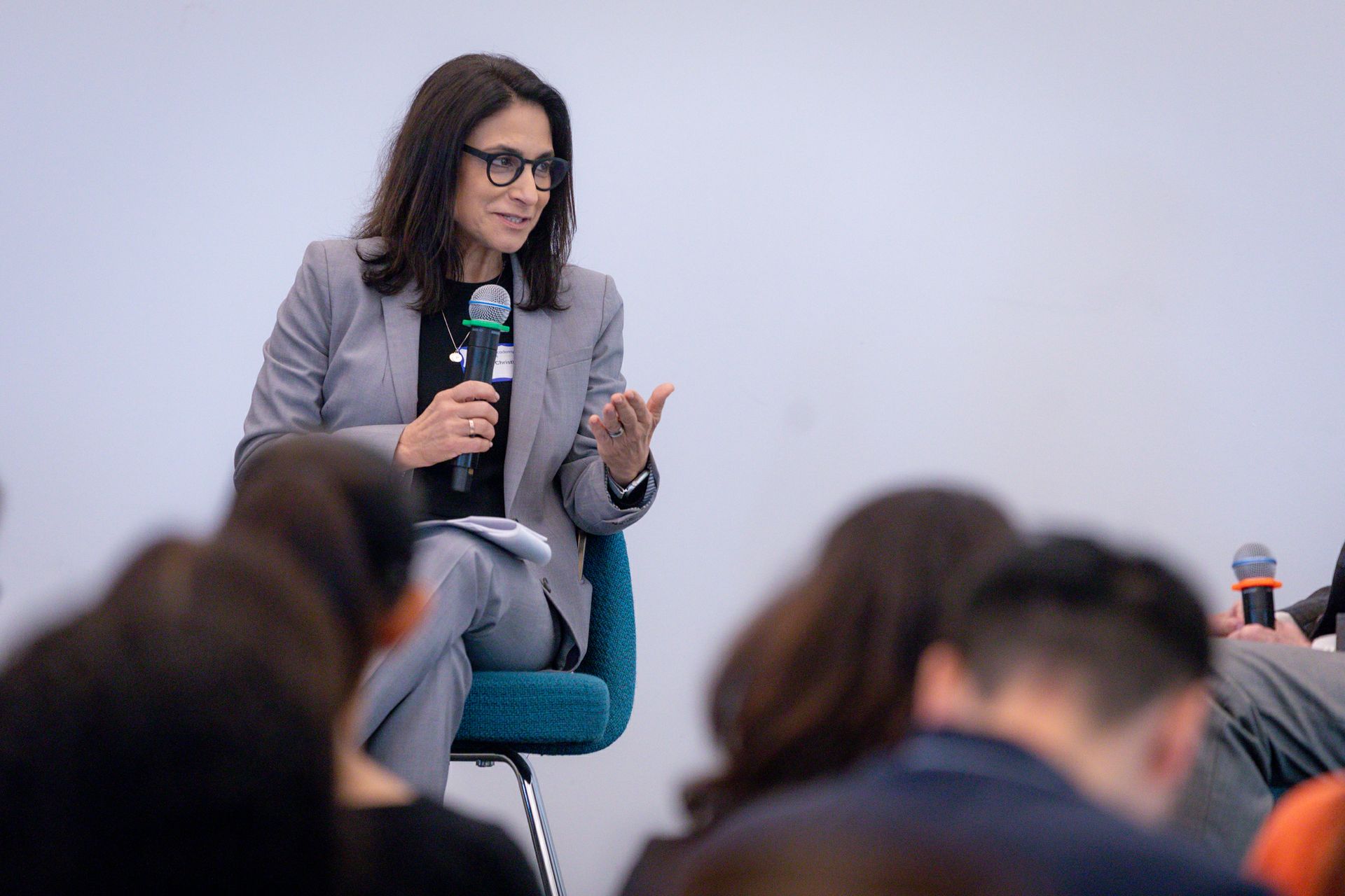 Christina Christie speaking into a microphone while seated before an audience at the Geffen Academy.