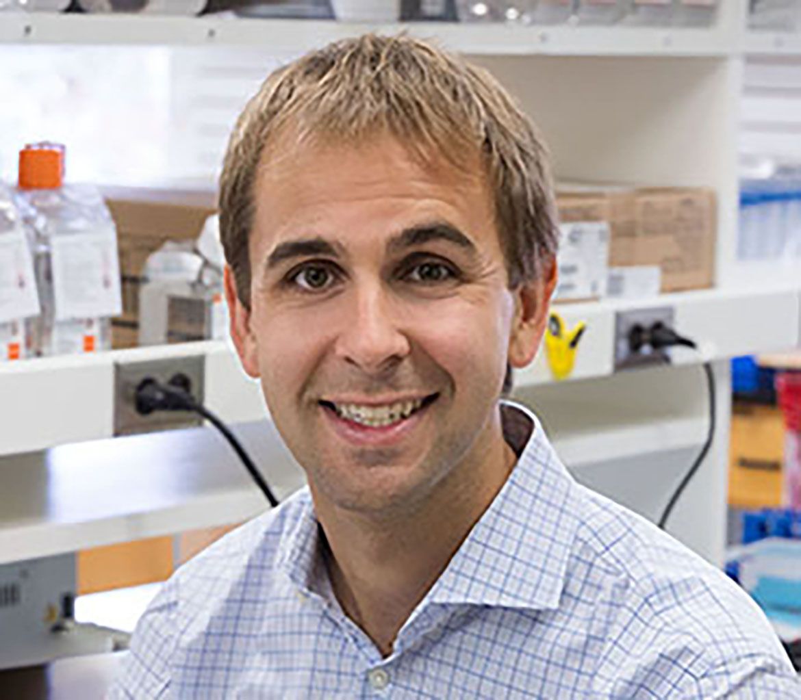 A portrait of Michael Lawson smiling in a laboratory setting.